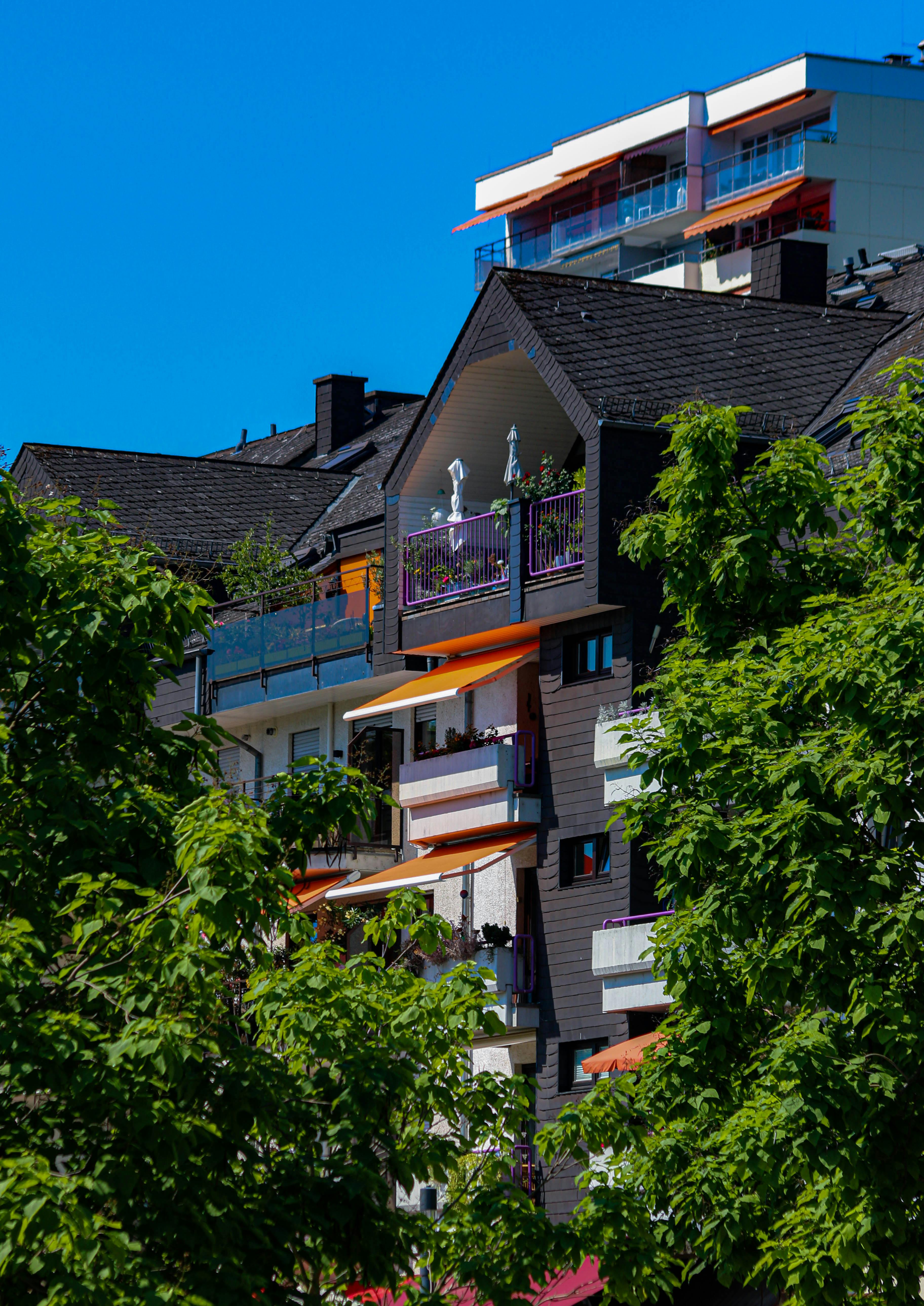 בניין מגורים מודרני עם מרפסות וסוככים כתומים | Modern Residential Building with Balconies and Orange Awnings