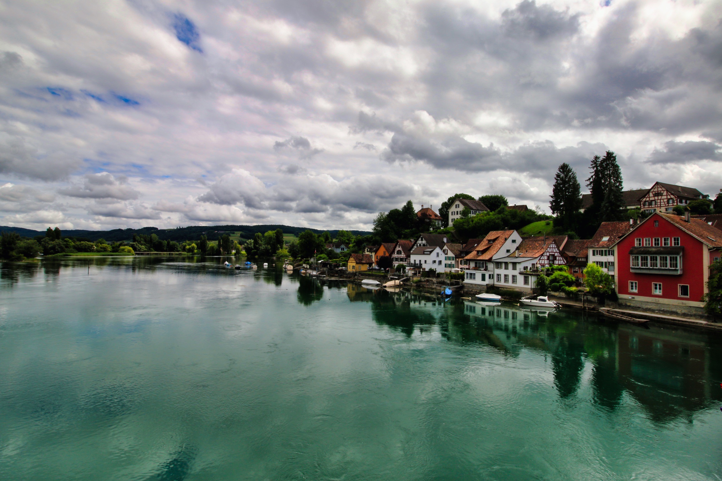 עיירה ציורית על גדת נהר משתקפת במים תחת שמיים מעוננים | Picturesque Town on a Riverbank Reflected in the Water under Cloudy Skies