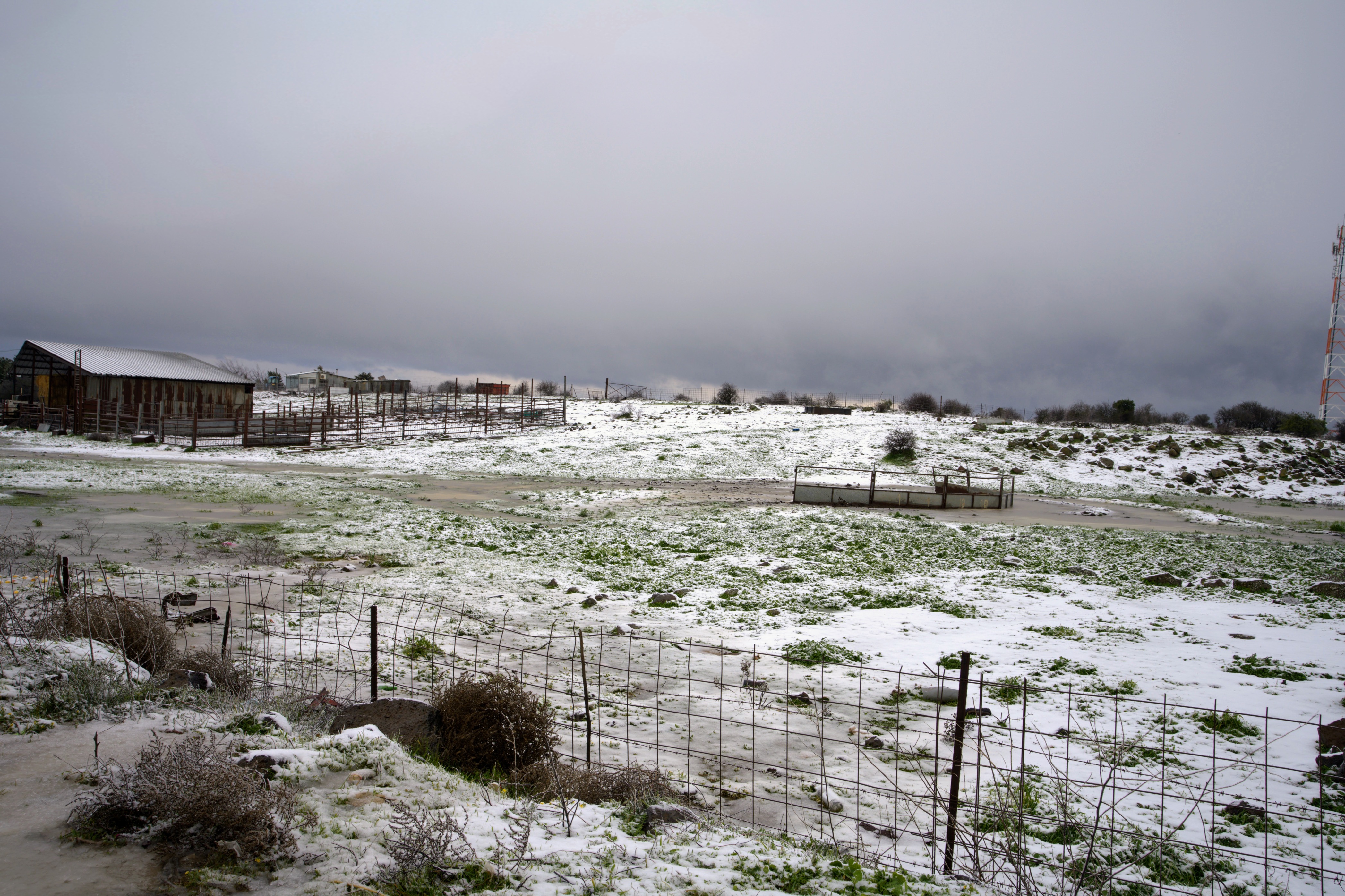 נוף חורפי מושלג של חווה חקלאית תחת שמיים קודרים ומעוננים | Snowy Winter Landscape of an Agricultural Farm under Gloomy and Cloudy Skies