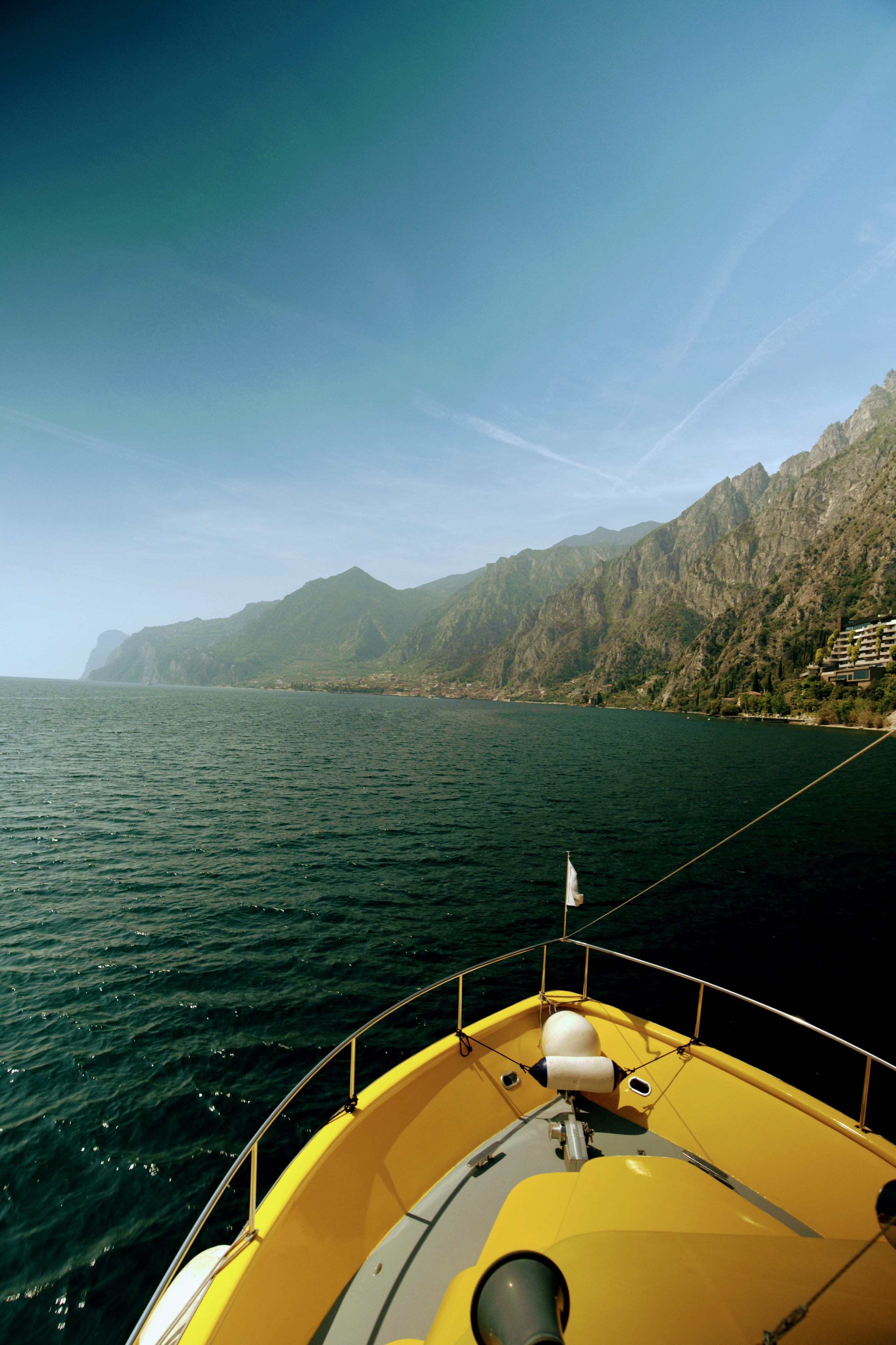 נקודת מבט מחרטום של סירה צהובה השטה באגם למרגלות הרים תלולים | POV from the Bow of a Yellow Boat Sailing on a Lake at the Foot of Steep Mountains