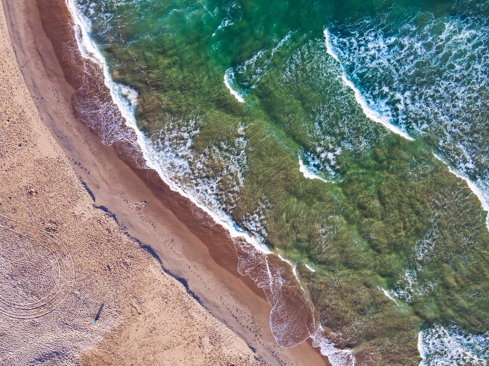 מבט מלמעלה על גלי ים נשברים אל חוף חולי | Top View of Sea Waves Breaking on Sandy Beach