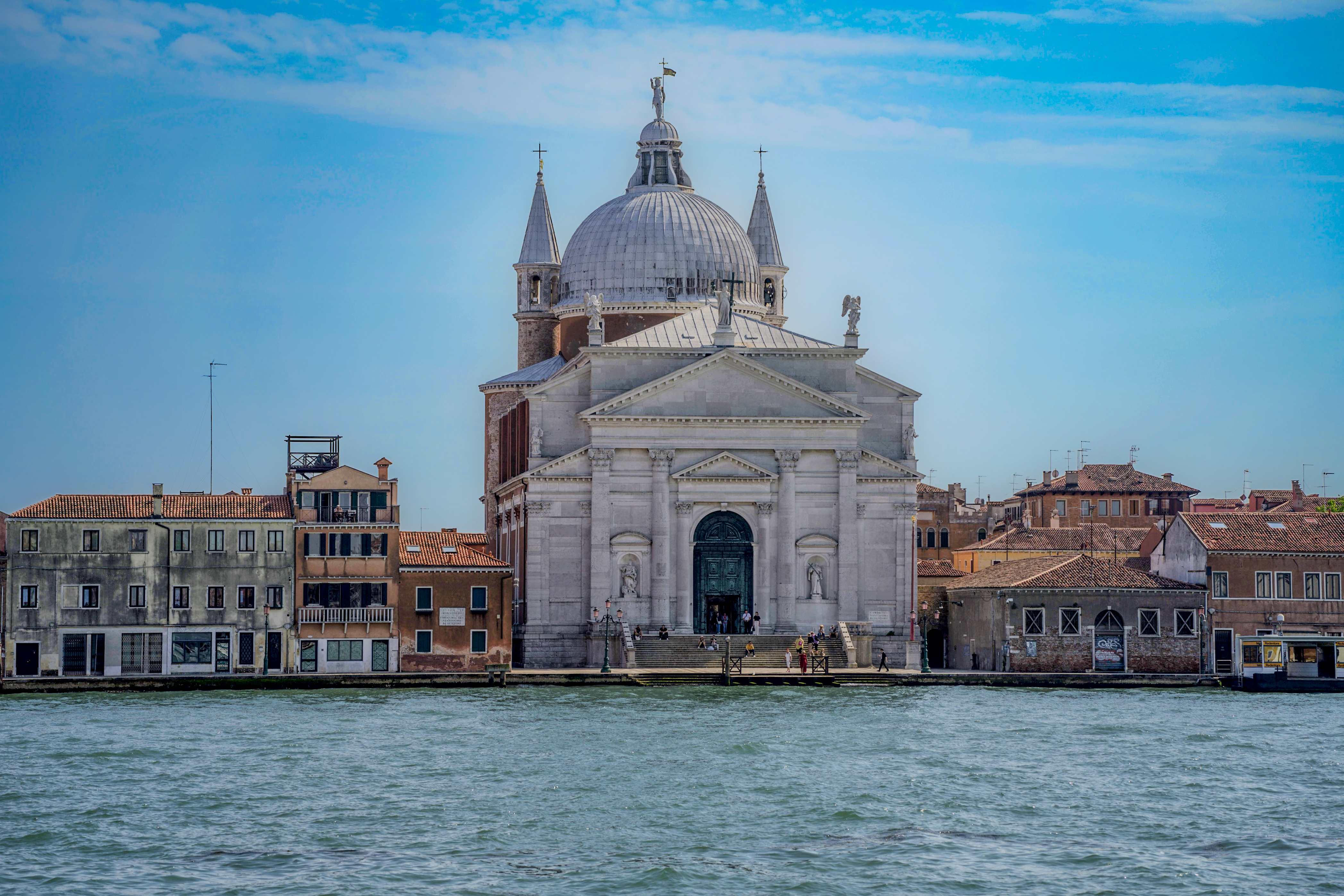 מבט מהמים אל כנסייה קלאסית עם כיפה ומבנים היסטוריים בוונציה